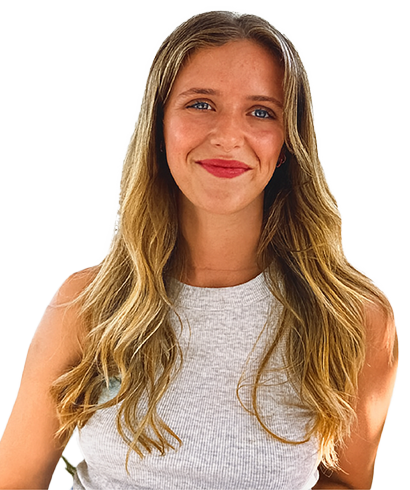 Eine junge Frau mit langen, gewellten blonden Haaren und blauen Augen lächelt in die Kamera. Sie trägt ein ärmelloses, hellgraues Oberteil und steht vor einem schlichten weißen Hintergrund.